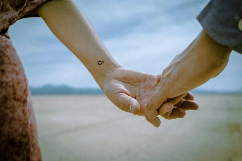 a close up of two people holding hands, a tattoo, trending on pexels, hand - tinted, landscape photo, ilustration, skin