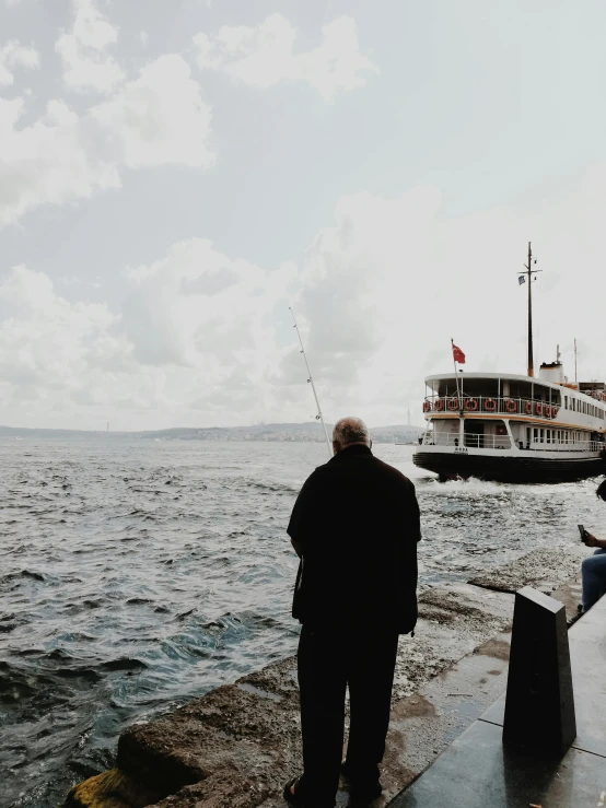 a man standing next to a body of water, by Niyazi Selimoglu, people watching around, high quality image, ship on lake, saying