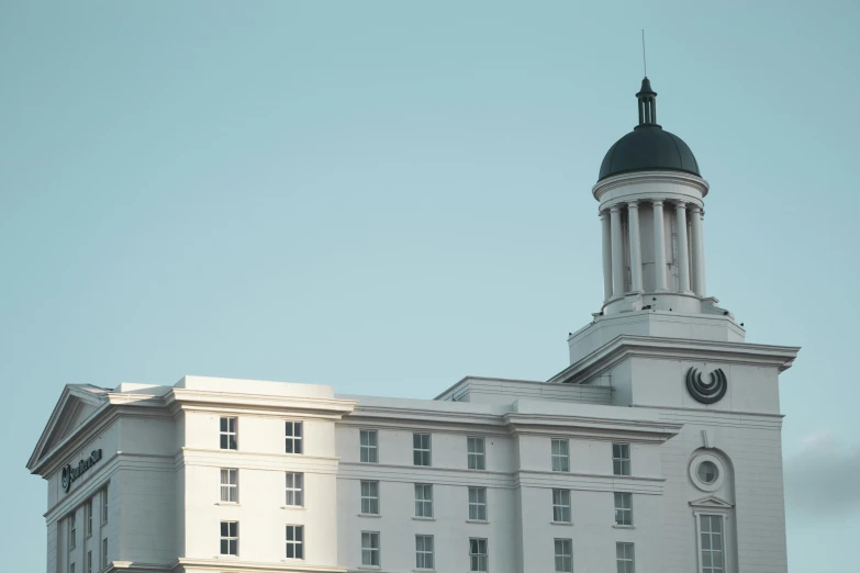 a large white building with a clock tower, inspired by Rachel Whiteread, unsplash, neoclassicism, alabama, hotel, palladium, university