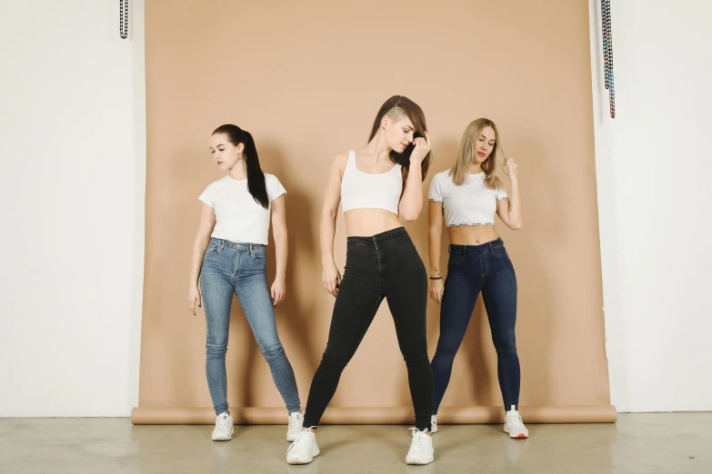 a group of young women standing next to each other, by Adam Marczyński, trending on pexels, aestheticism, black extremely tight jeans, dressed in a white t shirt, three women, multiple poses