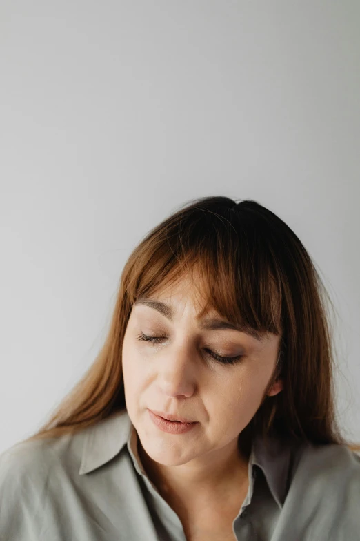 a woman sitting at a table with a plate of food, a character portrait, trending on pexels, hyperrealism, brown bangs, exhausted face close up, on grey background, professional profile photo