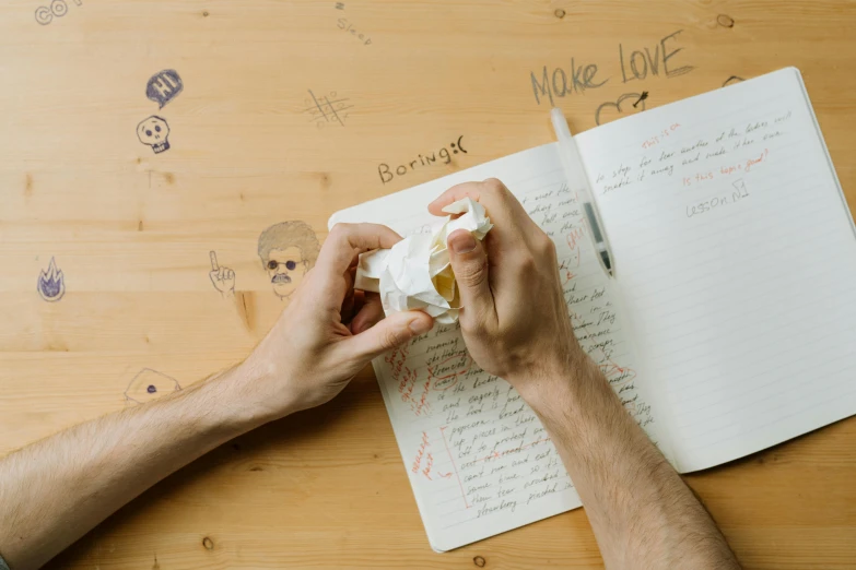 a person sitting at a table writing on a piece of paper, an album cover, by Julia Pishtar, pexels contest winner, papier - mache, writing in journal, tabletop role playing game, holding a milkor mgl