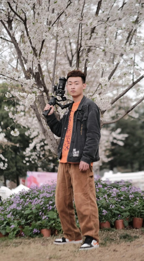 a man taking a picture of a blooming tree, inspired by Russell Dongjun Lu, unsplash, low quality photo, fullbody photo, 中 元 节, jacket