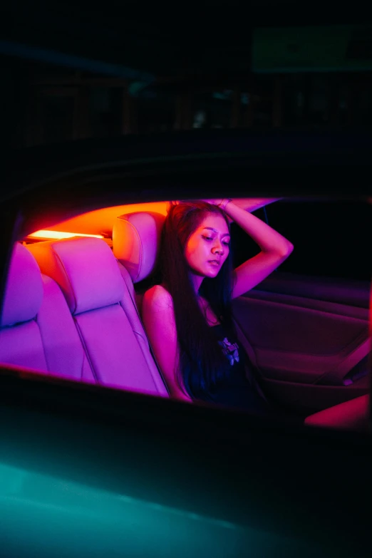 a woman sitting in the passenger seat of a car, an album cover, inspired by Elsa Bleda, synchromism, rgb lights, fluorescent skin, nightlife, orange lights