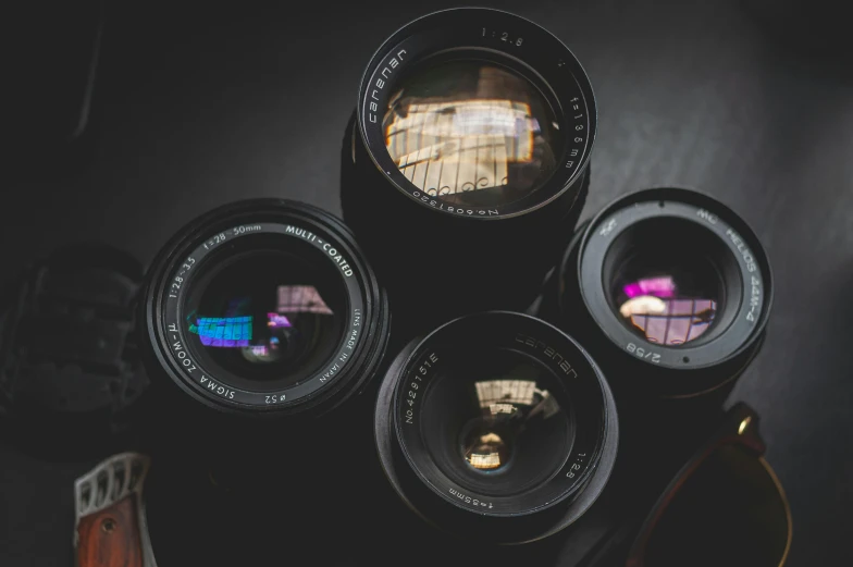 a couple of camera lenses sitting on top of a table, a picture, by Andrée Ruellan, unsplash, photorealism, looking up at camera, low-light photograph, aperture science, medium format