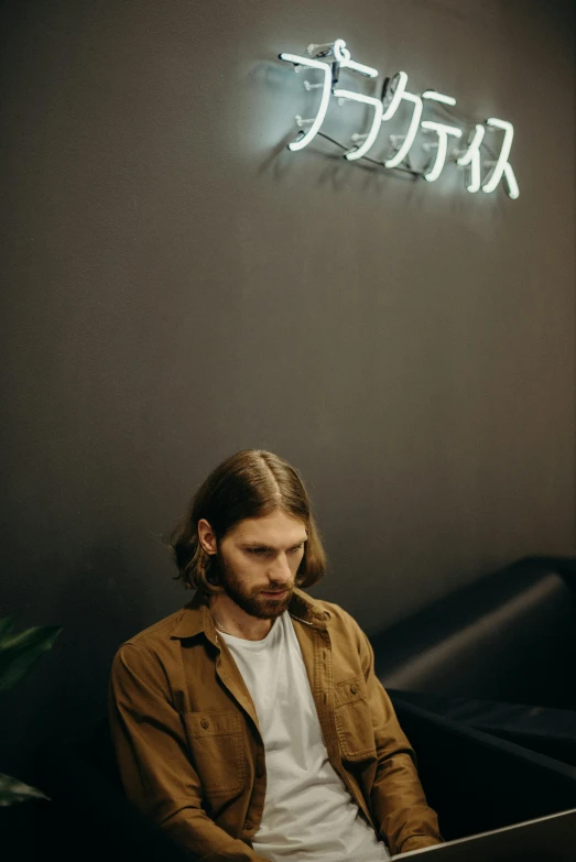 a man sitting in front of a laptop computer, an album cover, by Cosmo Alexander, pexels contest winner, waiting room, mid long hair, good lighted photo