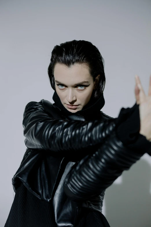 a woman in a black leather jacket posing for a picture, an album cover, inspired by Jean Malouel, unsplash, bauhaus, actor, arya stark, iris van herpen, fighting pose