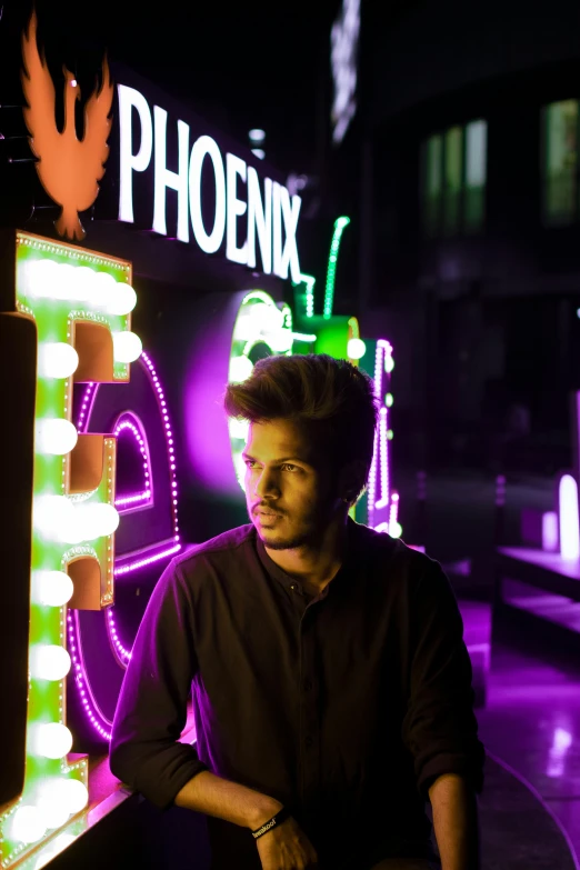 a man standing in front of a neon sign, pexels contest winner, phoenix head, profile image, university, mohamed chahin style