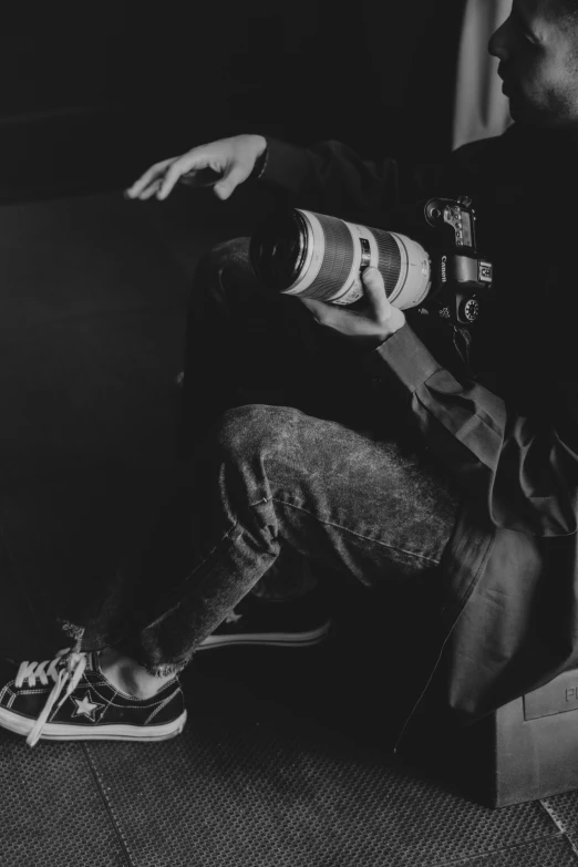 a man sitting on a couch with a bottle of beer, a black and white photo, unsplash, realism, standing on a skateboard, holding nikon camera, lit from bottom, bladee from drain gang