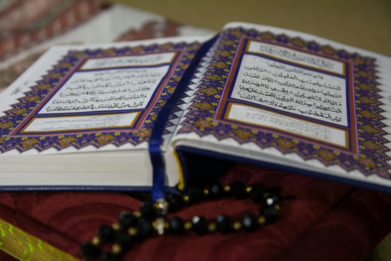 a close up of a book with a rosary on it, hurufiyya, ap, contain