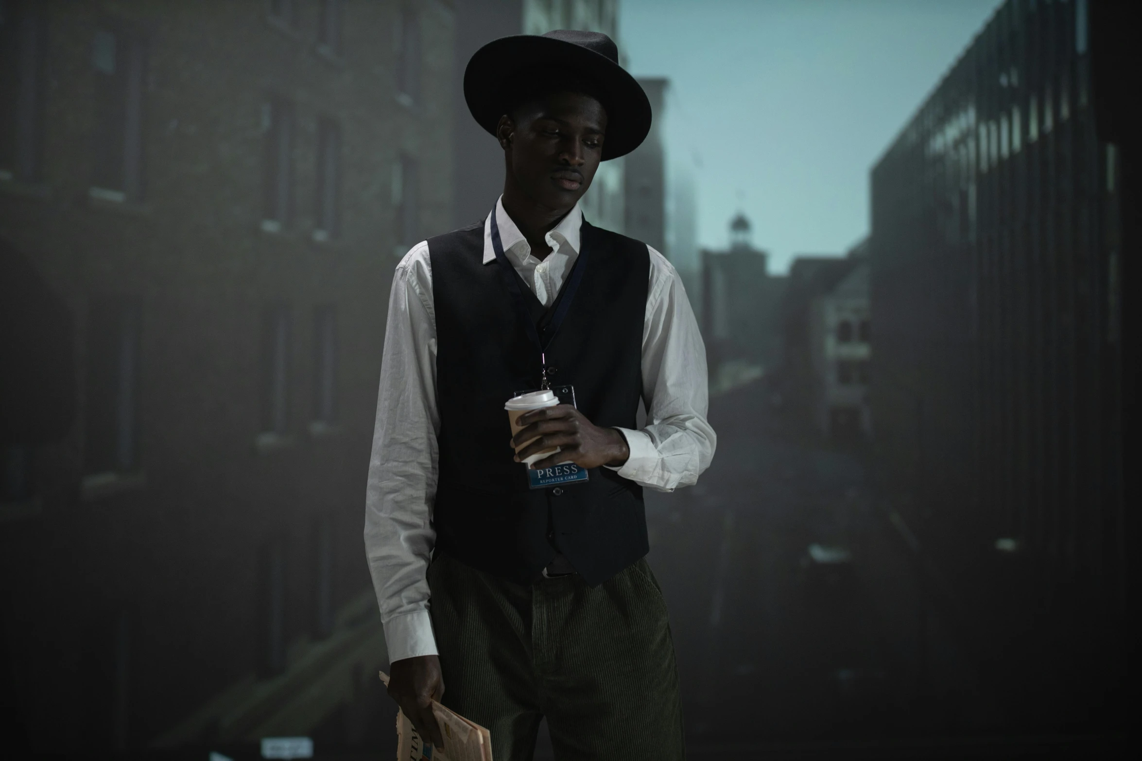 a man standing in the middle of a city holding a cup of coffee, harlem renaissance, spooky netflix still shot, marvelous designer, adut akech, tipping his fedora