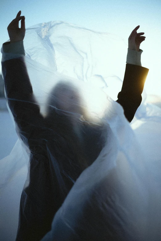 a person standing on top of a snow covered field, an album cover, unsplash, plasticien, soft translucent fabric folds, yohji yamamoto, backlight, veil