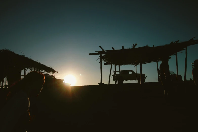 a couple of people that are standing in the dirt, a picture, unsplash contest winner, renaissance, sun shines down on the car, huts, sukkot, silhouetted