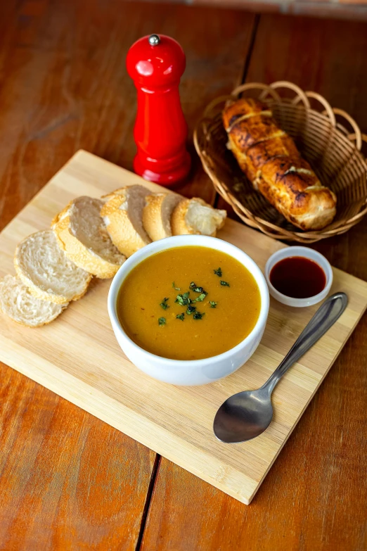 a bowl of soup and some bread on a cutting board, daily specials, multicoloured, square, sun coast