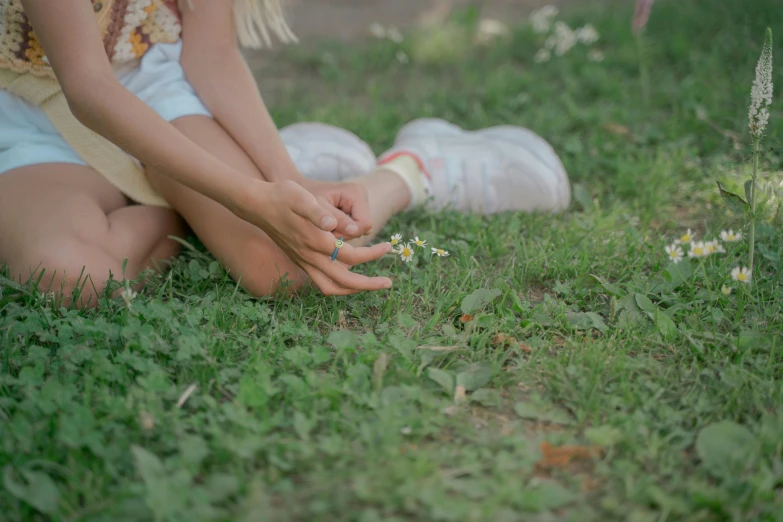 a woman sitting on top of a lush green field, an album cover, by Elsa Bleda, pexels contest winner, realism, kids playing, painted nails, holding daisy, legs intertwined