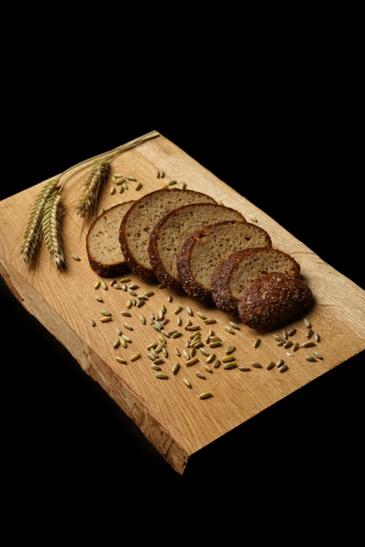 a wooden cutting board topped with slices of bread, seeds, thumbnail, german, hay