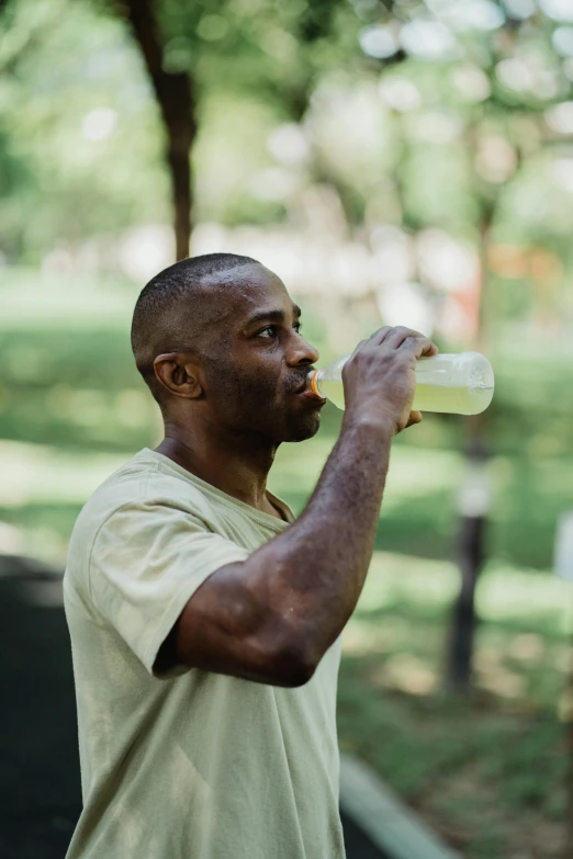 a man drinking from a bottle in a park, wearing a muscle tee shirt, greens), man is with black skin, profile image