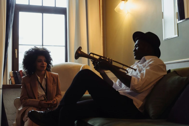 a woman sitting on a couch next to a man playing a trumpet, by Carey Morris, pexels contest winner, neo soul, profile image, two buddies sitting in a room, closed limbo room