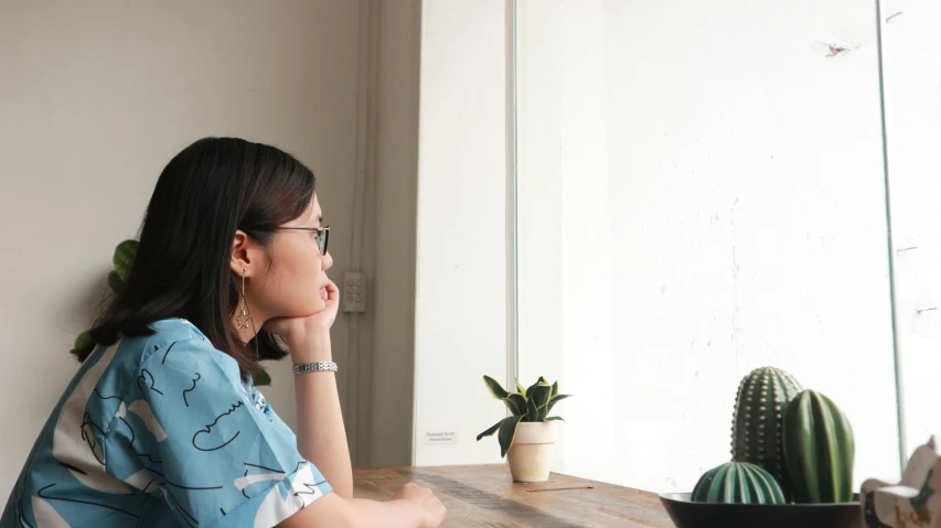 a woman sitting at a table looking out a window, a cartoon, unsplash, medium shot of two characters, asian female, realistic »