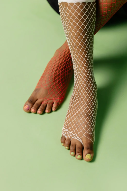 a woman's legs in fishnet stockings on a green surface, inspired by Sarah Lucas, trending on pexels, hyperrealism, aida muluneh, multi colored, ignant, tan complexion