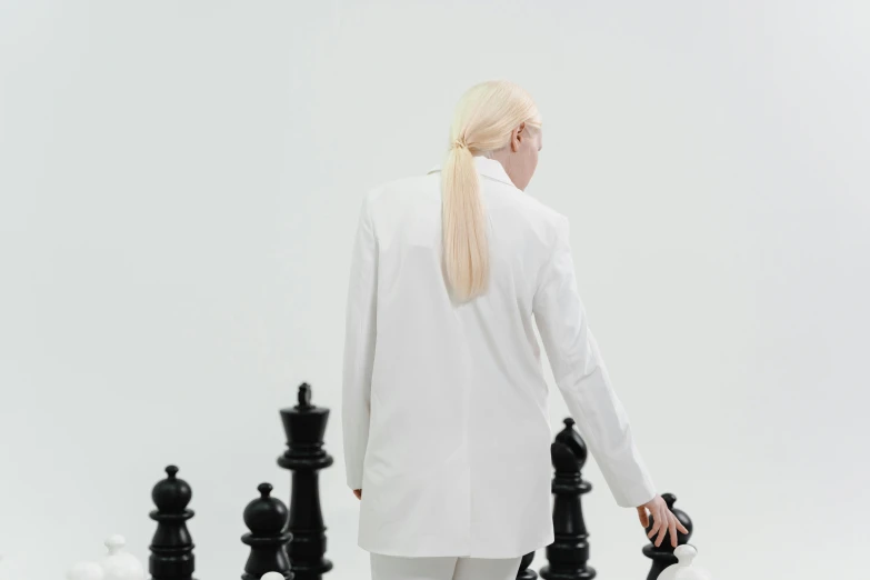 a woman in a white suit playing a game of chess, an album cover, inspired by Russell Dongjun Lu, unsplash, aestheticism, white ponytail hair, nadav kander, wearing a black noble suit, full growth from the back