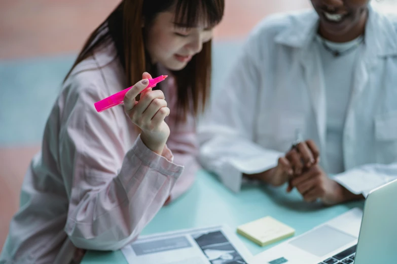 a couple of people sitting at a table with a laptop, pexels contest winner, analytical art, holding pencil, neon pink and black color scheme, a young asian woman, school curriculum expert