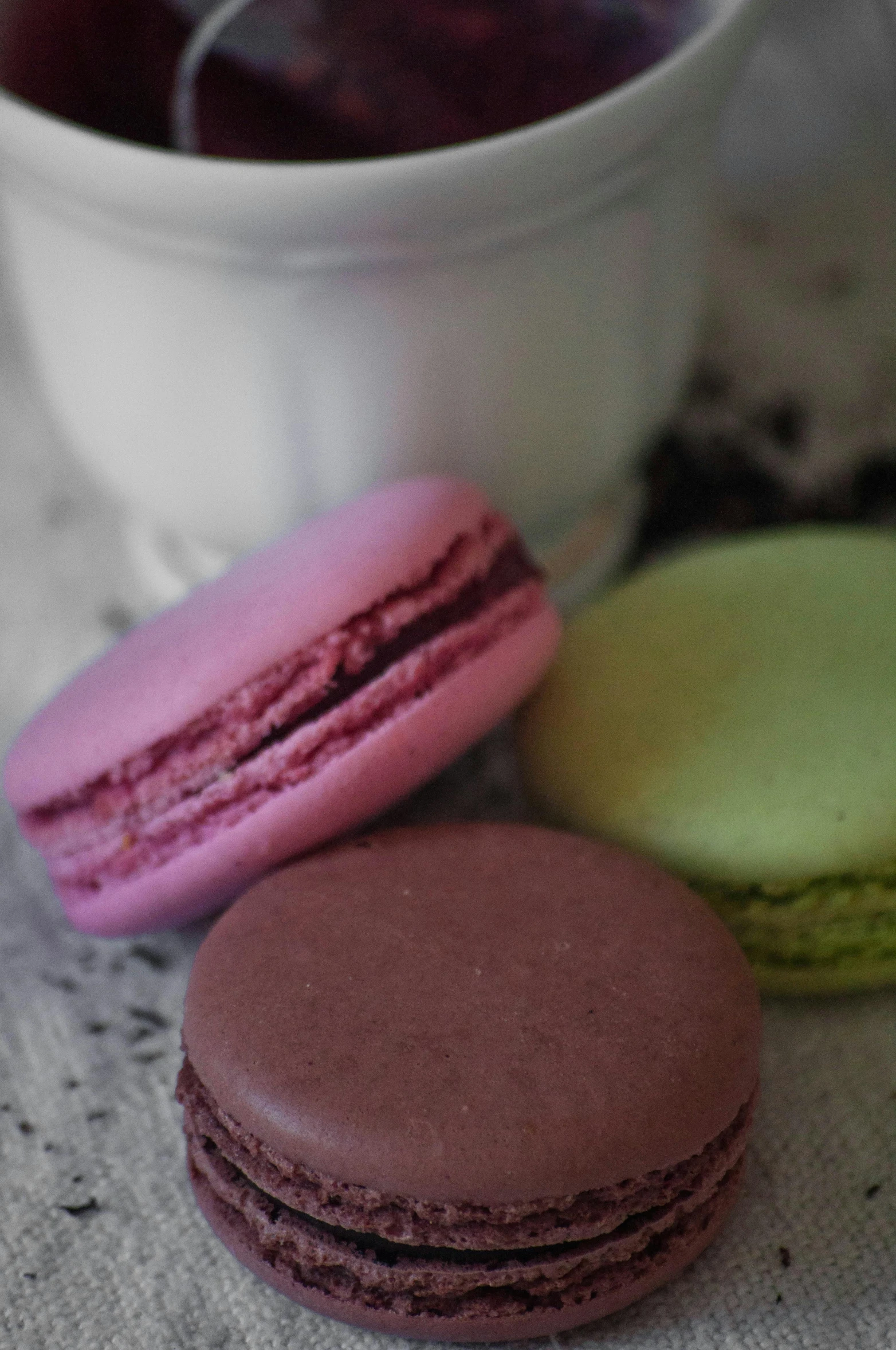 three macarons and a cup of tea on a table, a colorized photo, pexels, pink and green, made of glazed, chocolate, upclose