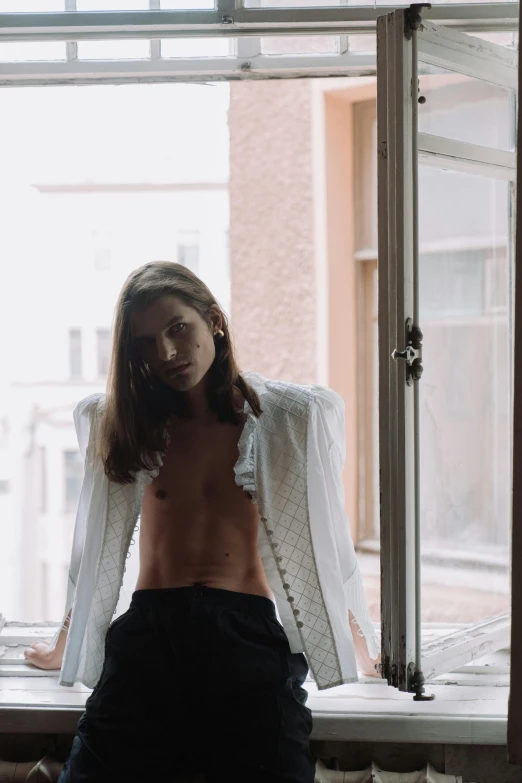 a shirtless man sitting on a window sill, an album cover, inspired by Elsa Bleda, unsplash, renaissance, in a flowing white tailcoat, young with long hair, androgynous person, wearing jacket