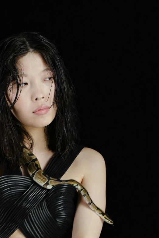 a woman in a black dress holding a snake, an album cover, inspired by Zhu Da, trending on pexels, jaeyeon nam, tifa lockhart portrait, close - up studio photo, helmut lang