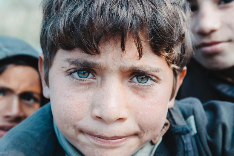 a close up of a young boy with blue eyes, by Kristian Zahrtmann, pexels contest winner, hurufiyya, an afghan male type, real life photo of a syrian man, peruvian boy looking, middle eastern skin