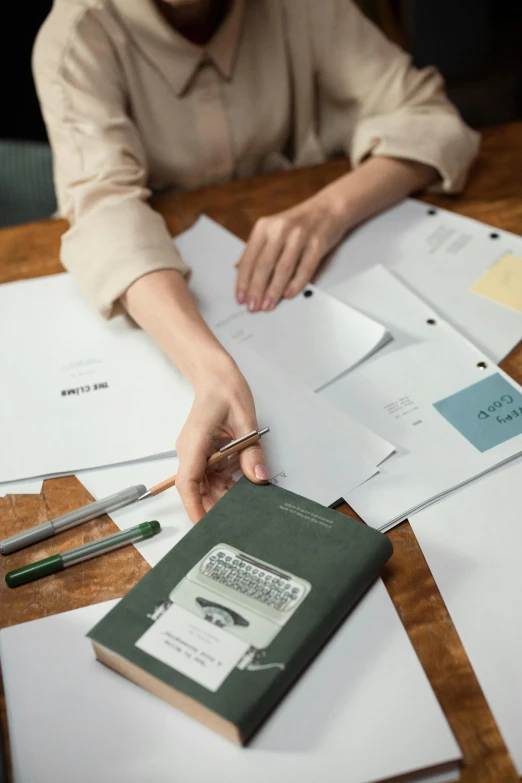 a woman sitting at a table with papers and a calculator, pexels contest winner, designer product, matte surface, textbooks and books, curated collections