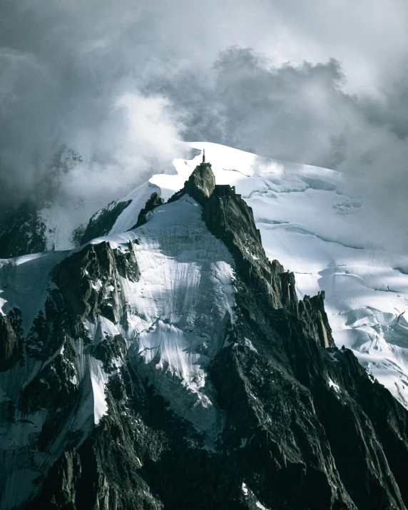 a man standing on top of a snow covered mountain, seen from a distance, ominous photo, towering, chamonix