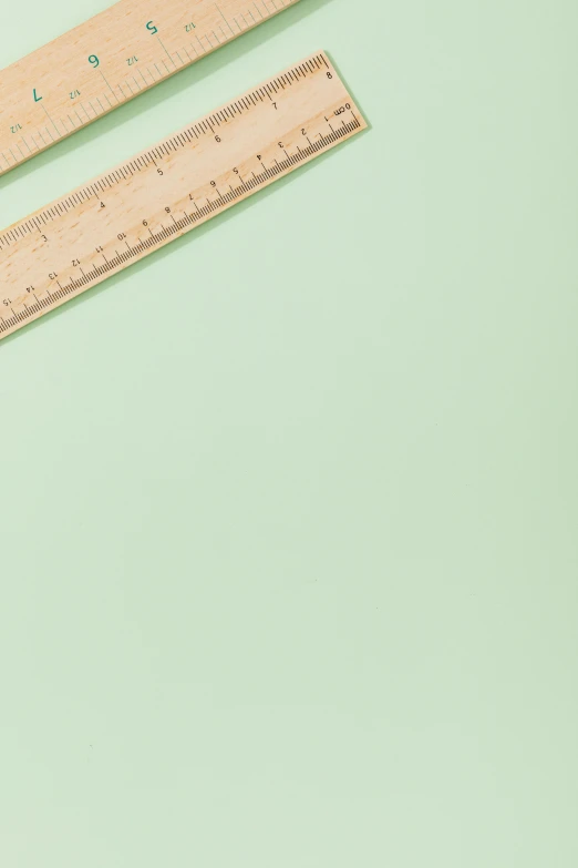 a pair of wooden rulers sitting on top of a green surface, gradient pastel green, 2019 trending photo