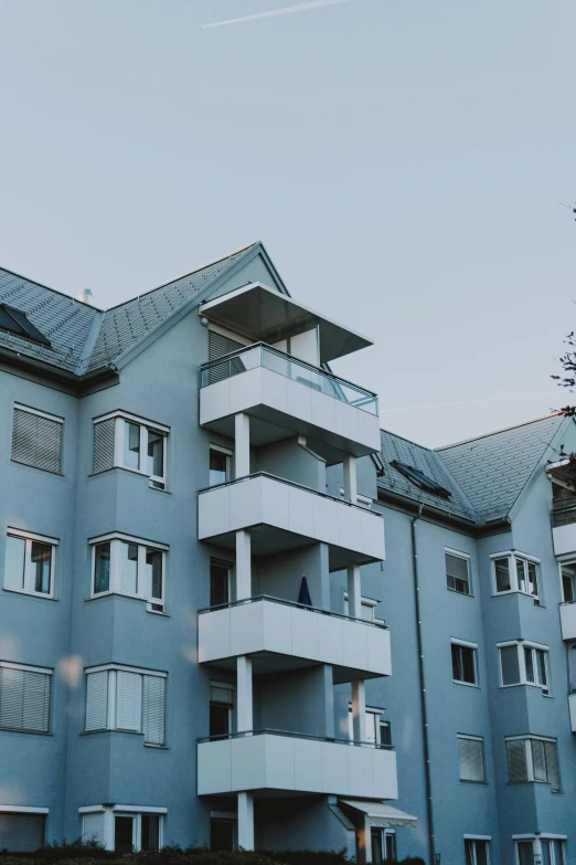 a tall building with lots of windows and balconies, unsplash, modernism, reykjavik, low quality photo, suburb, grey and blue theme