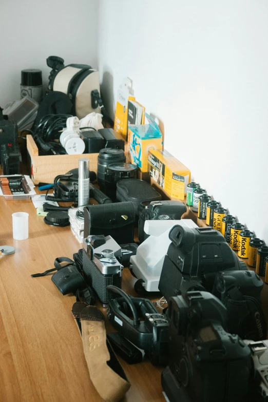 a bunch of cameras sitting on top of a wooden table, a picture, room full of computers, miscellaneous objects