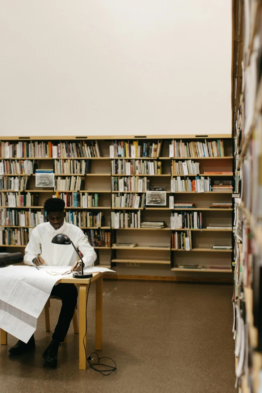 a man sitting at a table in a library, by Barthélemy Menn, unsplash, virgil abloh, kano), government archive, minna sundberg