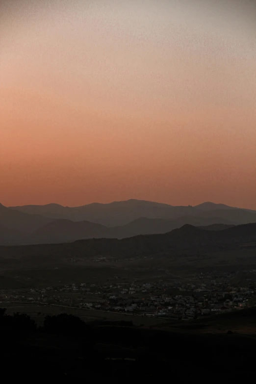 a man flying a kite on top of a lush green field, by Hubert van Ravesteyn, unsplash contest winner, vista of a city at sunset, deserts and mountains, panorama, very smoky