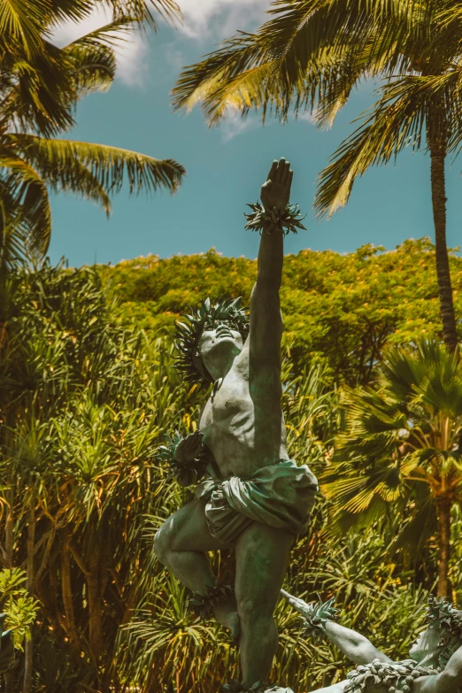 a statue sitting in the middle of a lush green forest, a palm tree, with arms up, tropical location, iconic