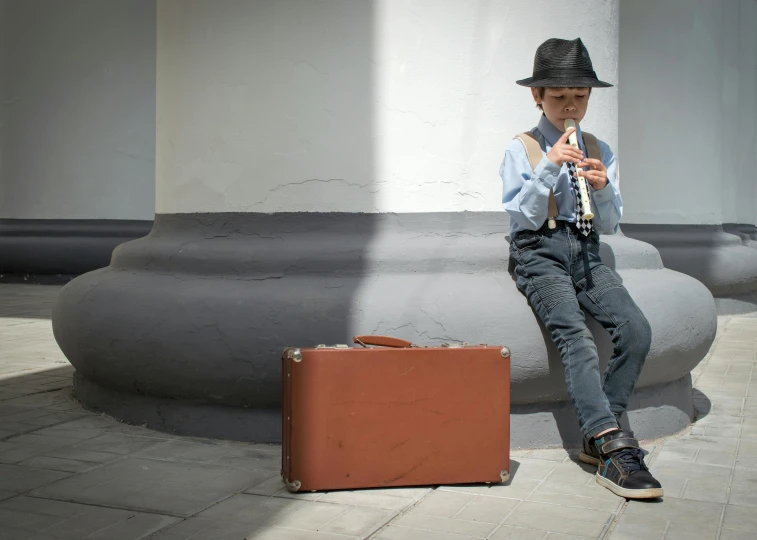 a man sitting on a bench next to a suitcase, inspired by Joseph Beuys, pexels contest winner, kids, mini model, brown, performing