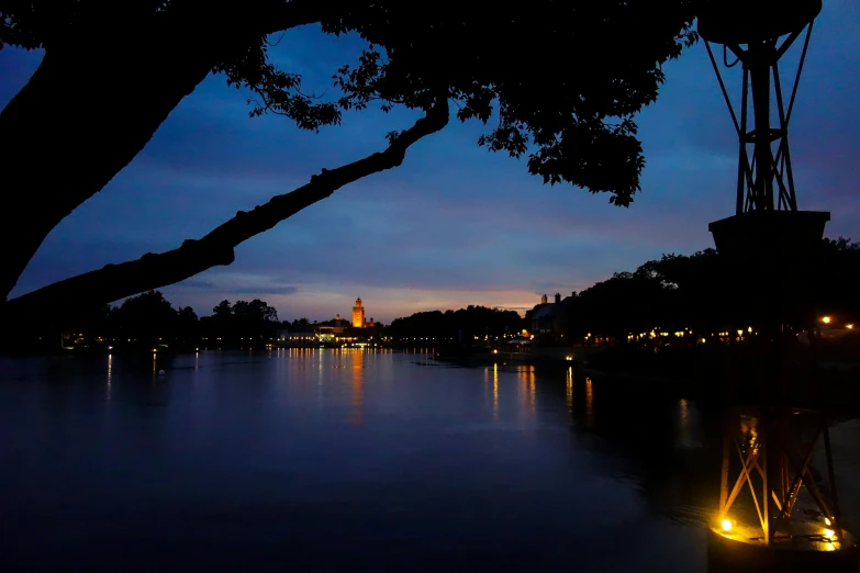 a large body of water with a clock tower in the background, by Jan Tengnagel, pexels contest winner, evening lanterns, angkor thon, city lights made of lush trees, seville