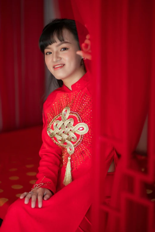 a woman in a red dress sitting on a bed, inspired by Tang Di, happening, ao dai, portrait image, square, medium-shot