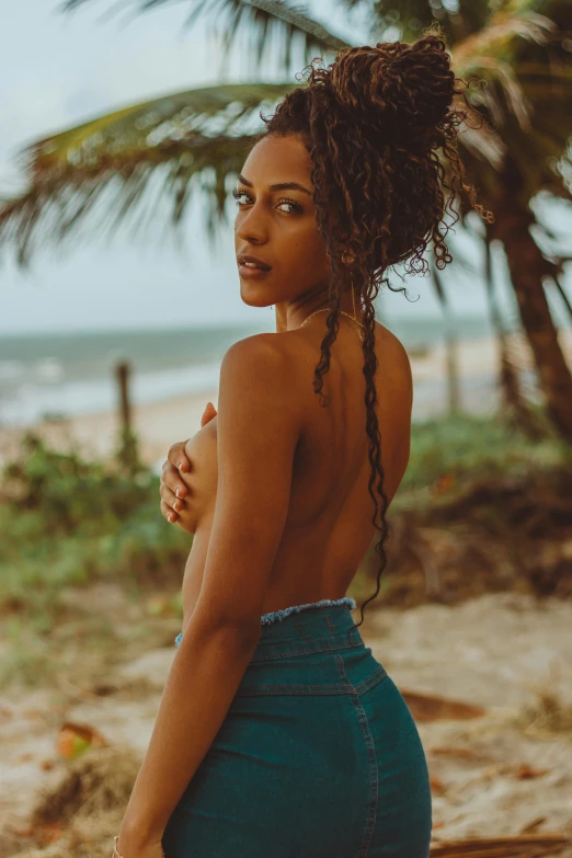 a woman standing on top of a sandy beach, trending on pexels, sexy girl with dark complexion, dreads, curls and curves, colombian