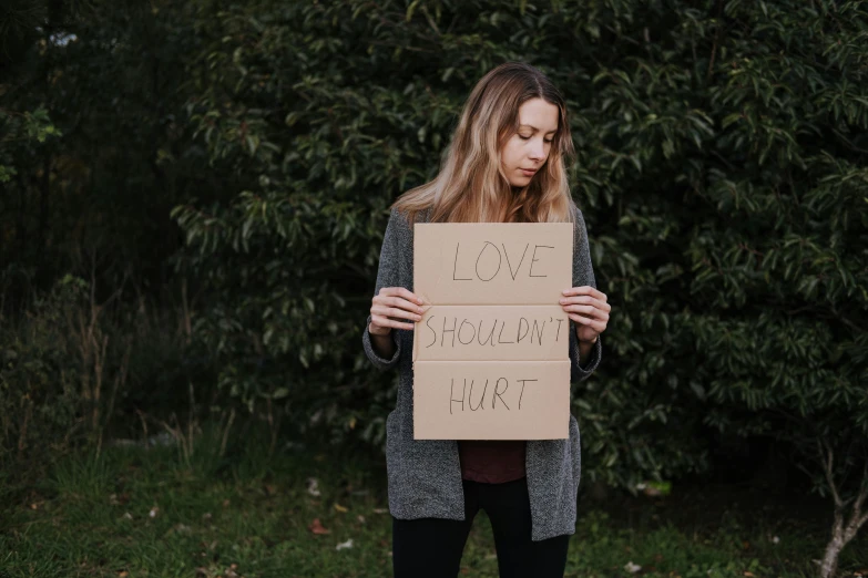a woman holding a sign that says i love holding hurt, trending on pexels, hurufiyya, depressed, outdoor photo, cardboard, profile image