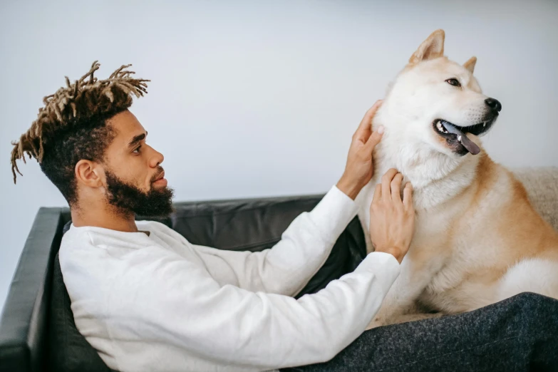 a man sitting on a couch petting a dog, trending on pexels, with afro, long spikes, white, 1 4 9 3