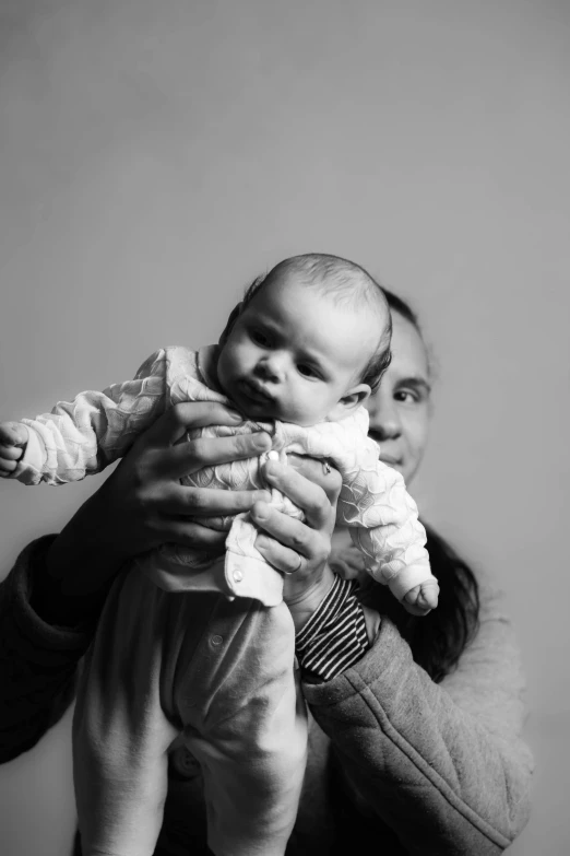 a woman holding a baby in her arms, a black and white photo, unsplash, dada, 'white background'!!!, father, bella poarch, show