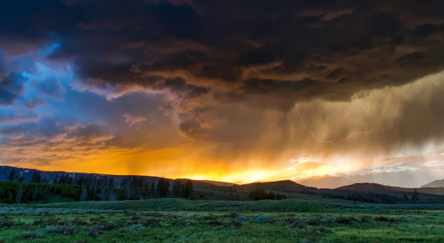 a storm is coming over a field with mountains in the background, by Joe Stefanelli, unsplash contest winner, sunset panorama, yellow lightning, wyoming, thunder storm and forest on fire