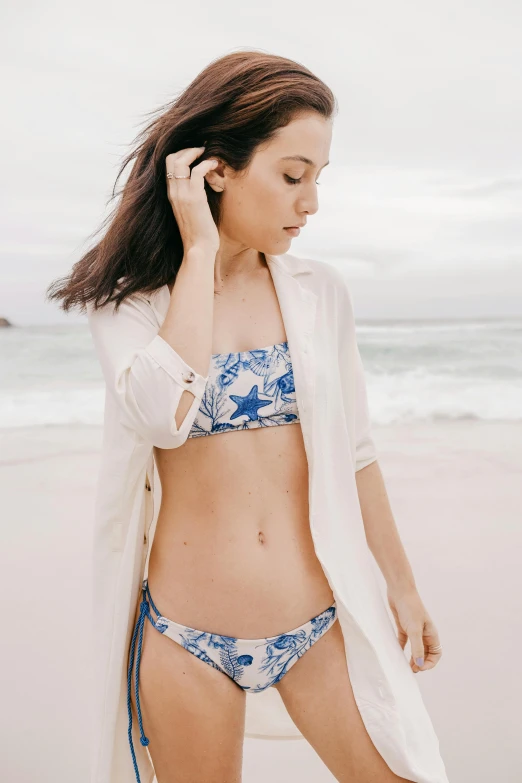 a woman standing on top of a beach next to the ocean, floral patterned skin, belly button showing, linen, gemma chen