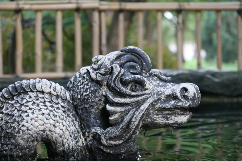 a statue of a dragon in the water, inspired by Xuande Emperor, unsplash, ashford black marble sculpture, delightful surroundings, grey, low detail