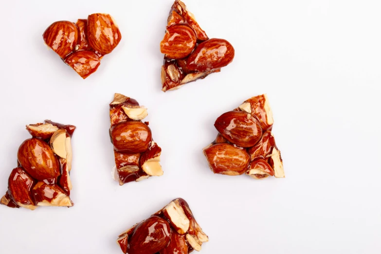 a number of pieces of food on a white surface, by Nicolette Macnamara, trending on pexels, hurufiyya, brittle. highly detailed, caramel, flat triangles, reds