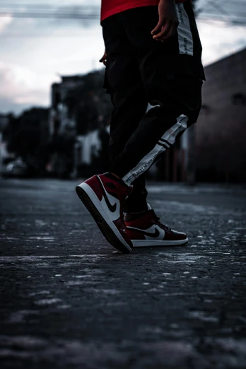 a person wearing a red shirt and black pants, inspired by Jordan Grimmer, trending on pexels, realism, sneaker photo, low light, red white and black, injured